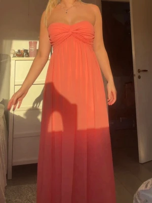 Balklänning  - Säljer en axelbandslös långklänning i en snygg korallrosa/orange färg. 🧡🧡🧡 Endast testad då jag ska ha en annan till min bal! Så så fin verkligen! Passar även jätte fin till midsommar/bröllop🩷