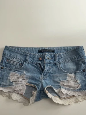 Ljusa jeansshorts  - Ett par lågmidjade ljusblåa jeans shorts ifrån bershka med lite slitningar och fin under ficka. De har även en volange kant. Stolek 34