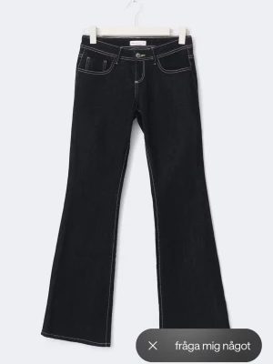 Mörkblå Low Waist jeans från Gina  - Snygga mörkblå bootcut jeans med vita kontrastsömmar och klassisk femficksdesign. Jeansen har låg midja och utsvängda ben, perfekta för en trendig look. Tillverkade i denim med en cool vibe.