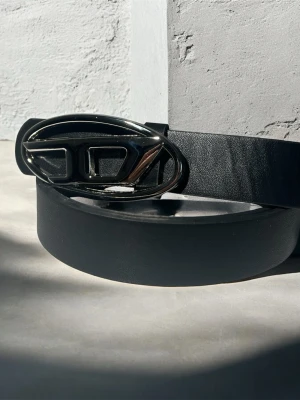 Vintage Diesel Belt bälte  - Snyggt svart bälte från diesel i slätt läder med ett stilrent, ovalt metallspänne i silverfärg. Perfekt accessoar för att lyfta din outfit med en modern touch och exklusiv känsla.
