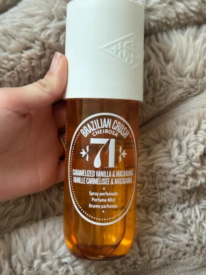 Sol de Janeiro Brazilian Crush 71 - Parfymmist med doft av karamelliserad vanilj och macadamia från Sol de Janeiro. Flaskan är genomskinlig med bärnstensfärgad vätska och har ett vitt lock. Perfekt för dig som gillar söta och nötiga dofter.