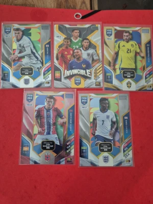 FIFA 365 fotbollskort, 5-pack - Fem stycken FIFA 365 fotbollskort från Panini, med olika spelare och nationer. Korten har färgglada designer och detaljerade illustrationer, vissa med specialeffekter som holografisk yta. Perfekt för samlare eller fotbollsintresserade.                     20kr styck, 50 för Kulusevski och 80 för Invincible-kortet (rare)
