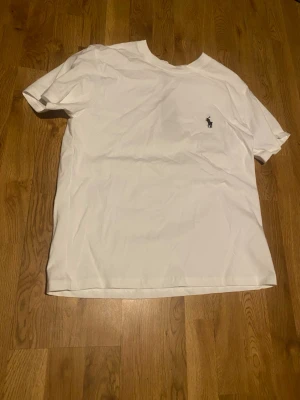 Vit t-shirt från Polo Ralph Lauren - Klassisk vit t-shirt från Polo Ralph Lauren med liten broderad logga på bröstet. T-shirten har rund halsringning och korta ärmar. Perfekt basic-plagg i mjuk bomull som funkar till allt.