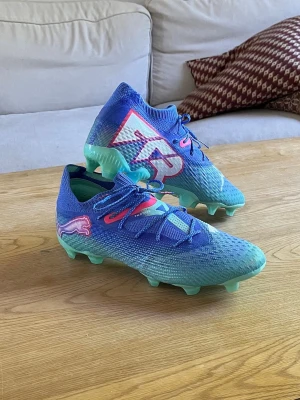 Blåa Puma Future fotbollsskor - Säljer ett par blåa Puma Future fotbollsskor som är endast använda en gång på träning. Jag säljer de då de var för smala för mig. Pris kan diskuteras!!!