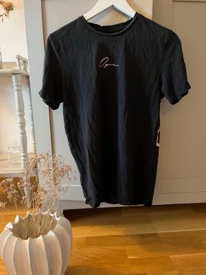 Svart t-shirt från Jack & Jones - Snygg svart t-shirt från Jack & Jones Originals med logga på bröstet. Klassisk rund halsringning och korta ärmar. Regular fit för en bekväm passform. Perfekt till jeans eller shorts.