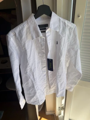 Vit linneskjorta från Polo Ralph Lauren - Säljer denna snygga skjortan då den är lite för liten för mig. Storlek M men sitter mer som S därav storleken. Helt nytt skick. Perfekt när sommaren närmar sig!