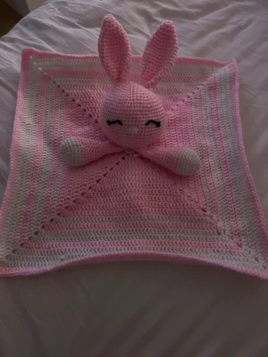Egen virkade snuttefilt med huvud - Hej, säljer denna handvirkade kanin-snuttefilt. Den är mjuk, mysig och perfekt för små händer att hålla i. Handgjord av mig i rosa/vitt garn med söta detaljer. (Finns bara i ett exemplar). Filten är 36cm lång, armar, huvud och öron är ca 10cm lång. Skriv för mer frågor!