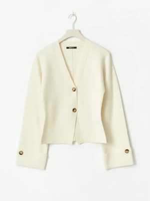 Krämvit kofta med knappar från Ginatricot - Snygg krämvit kofta från Ginatricot med stora bruna knappar framtill och på ärmsluten. Koftan har en djup v-ringning och breda muddar, perfekt för lager-på-lager och en clean look.