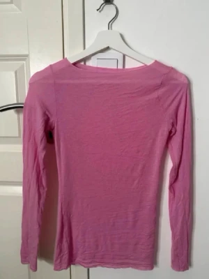 Rosa långärmad topp intimissimi - En enkel och stilren rosa långärmad topp med rund halsringning. Perfekt att matcha med jeans eller kjol för en avslappnad look. Tunn och mjuk i materialet, sitter snyggt mot kroppen.