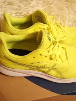 Gula Asics Patriot 13 sneakers - Snygga sneakers från Asics i modellen Patriot 13. Skorna är helgula med vita sulor och har mesh-överdel för bra andningsförmåga. Klassisk snörning och låg profil gör dem perfekta för en sportig look.