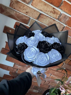 Bukett med svarta och vita rosor - Säljer en unik bukett med konstgjorda svarta och vita rosor, dekorerad med två dekorativa fjärilar i metall. Blommorna är inslagna i svart papper och buketten hålls ihop med ett vitt band. Perfekt som present eller dekoration.