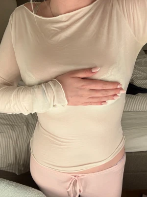 Ljusbeige långärmad topp - Superfin ljusbeige långärmad topp i tunnt tyg med tight passform. Toppen är genomskinlig och har en enkel, stilren design med rund halsringning. Perfekt att styla lager på lager eller som statement-piece.