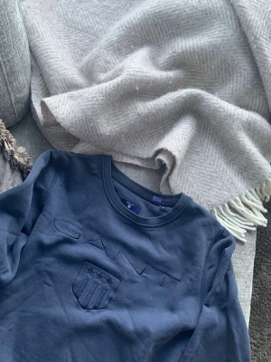 Mörkblått set från GANT - Säljer ett mörkblått mjukisset från GANT med sweatshirt och matchande byxor. Tröjan har rund halsringning och broderad logga med sköld framtill. Byxorna har resår i midjan och diskret logga på benet. Perfekt för en chill och snygg look.