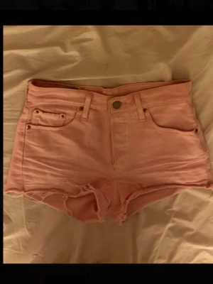 Rosa Levi's 501 jeansshorts - Säljer ett par ljusrosa jeansshorts från Levi's modell 501. Klassiska fem fickor och råa, fransiga benslut. Dom är högmidjade men jag brukar ha dom mellan midjade, dvs under naveln💕💕