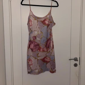 Pastellfärgat klänning med mönster - Klänning med tunna axelband och ett unikt pastellmönster i rosa, lila och guldtoner. 