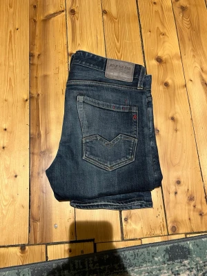 Replay Blue Jeans mörkblå jeans - Mörkblå jeans från Replay Blue Jeans med klassisk femficksdesign och snygga slitningar. Jeansen har raka ben och tydliga sömmar på bakfickorna. Tillverkade i denim med en autentisk tvättad look.