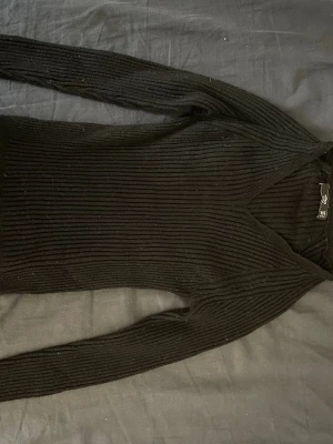 Svart ribbstickad tröja V-ringad - Säljer en svart ribbstickad tröja från mango. med V-ringning och långa ärmar. Tröjan är figurnära och har en klassisk, enkel design som passar till det mesta. Perfekt basplagg för garderoben.