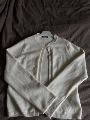 Vit kofta från Gina Tricot - Klassisk vit kofta från Gina Tricot med rund halsringning och en knapp framtill. Mjuk stickad kvalitet och långa ärmar. Använd fåtal gånger och är i väldigt bra skick🤩