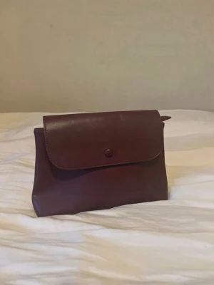 Mörkbrun necessär/clutch - Säljer denna jättefina och rymliga clutch/necessär då den inte kommer till användning! Köpt på en second hand så vet inte vad den är ifrån eller vad för material det är men det är nog ändå en bra läder imitation! I fint skick och jag har aldrig använt den!