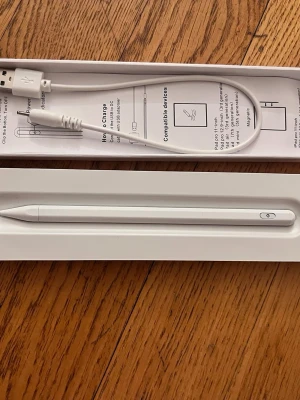 Active Stylus Pen med Palm Rejection - Säljer en vit Active Stylus Pen med Palm Rejection, perfekt för surfplattor och touchskärmar. Pennan är smal och stilren med en knapp på sidan och levereras med en USB-laddningskabel. Materialet är plast och designen är minimalistisk.