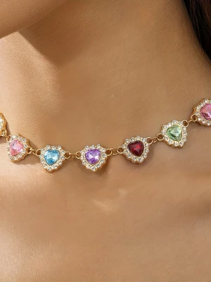 Halsband med hjärtformade färgade stenar - Säljer ett halsband med hjärtformade stenar i olika färger som blått, rött, grönt, rosa och lila. Stenarna är infattade i guldfärgad metall och omgivna av små klara pärlor som ger extra bling. Perfekt för dig som gillar färgglada accessoarer och vill sticka ut.