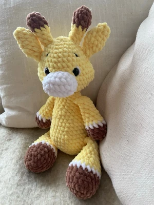 Virkad giraff Gul - Gul handvirkad giraff av mjukt chenillegarn. Mjukisdjuret är stoppad med polyesterfyllning och har säkerhetsögon av plast. Giraffen är ca 30 cm hög 🧶🦒 OBS! Pga plastögonen rekommenderas inte mjukisdjuret för barn under 3 år