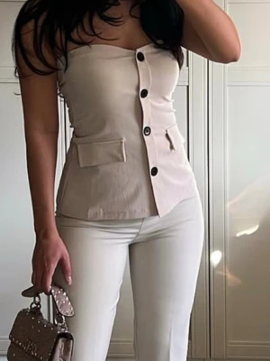 Beige axelbandslös topp från Gina  - Trendig beige axelbandslös topp med stora svarta knappar framtill och dekorativa fickor. Toppen är från Gina tricot i storlek xs 