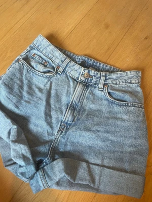 Blå jeansshorts - Säljer ett par klassiska blå jeansshorts. Shortsen har två bakfickor och tydliga sömmar. Perfekta för sommaren och lätta att matcha med olika toppar.
