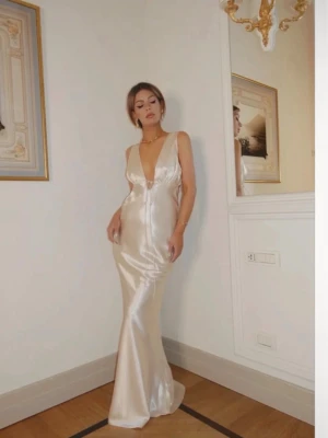 Klänning/balklänning  - Elegant långklänning i champagnefärgad satin med djup v-ringning och öppen rygg. Säljer den då jag hittat en annan, helt ny