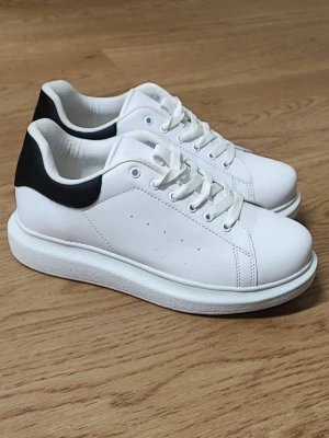 Vita sneakers med svart häl från Nelly - Vita sneakers från Nelly med svart detalj på hälen. Helt nya. Storlek 39.