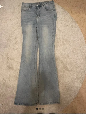 Ljusblå bootcut jeans - Snygga ljusblå bootcut jeans med klassisk femficksdesign och dragkedjegylf. Jeansen har en lätt tvättad look och utsvängda ben som ger en retrovibe. Perfekta att styla med sneakers eller boots. Materialet är denim i bomull.