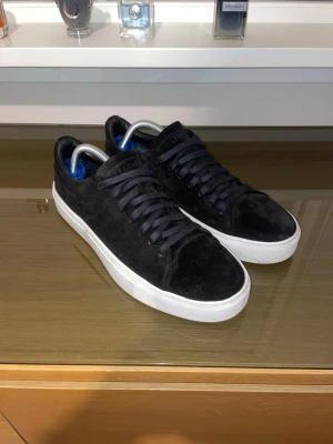 Svarta Legend sneakers i mocka - Säljer ett par nya svarta sneakers från Legend (använda 2 gånger) med ovandel i mjuk mocka och vita, tjocka gummisulor. Skorna har svarta skosnören och en låg silhuett. Nypris ca: 1400kr.
