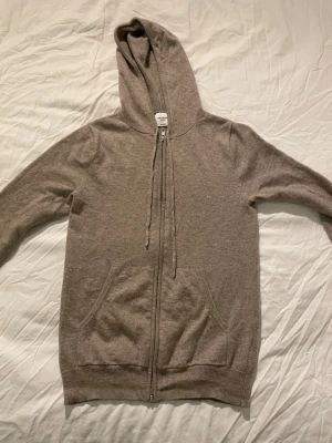 Beige cashmere hoodie John Henric - Mjuk och lyxig beige hoodie från John Henric i 100% cashmere. Dragkedja framtill, två fickor och justerbar huva med snören. Perfekt för dig som vill ha en stilren och bekväm hoodie med exklusiv känsla. Skick 9/10. Kan diskutera pris. Inga defekter. Passar mig som e 180.