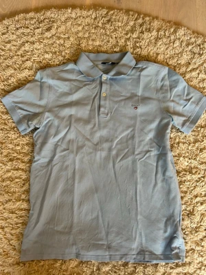 Ljusblå Gant Piké  - Ljusblå Gant Piké i storlek 158/164 cm. Bra skick, inga synliga tecken på slitage. Priset ej hugget i sten. Skriv gärna vid frågor!