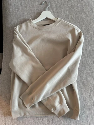 Beige sweatshirt från H&M Relaxed Fit - Säljer en beige sweatshirt från H&M Relaxed Fit. Tröjan har rund halsringning, långa ärmar och ribbade muddar vid ärmslut och nederkant. Materialet är mjukt och bekvämt, perfekt för en avslappnad stil. Enkel och stilren design som är lätt att matcha.