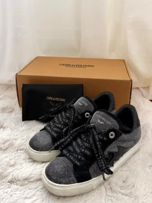 Zadig & Voltaire La Flash Sparkle sneakers - Snygga sneakers från Zadig & Voltaire i svart och grått/glittrigt tyg med detaljer i mocka. Skorna har vita sulor och svarta skosnören med logotyp. Klassisk låg modell med coola kontraster och diskret logga på plösen.