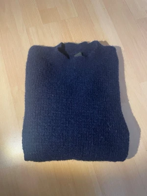 Mörkblå stickad tröja - Varan är köpt här på plick och jag säljer den för samma pris jag köpte den då jag inte använt den. Mysig mörkblå stickad tröja med rund hals och långa ärmar. Tröjan har en enkel, klassisk design och är tillverkad i ett mjukt, grovt stickat material som passar perfekt för kyligare dagar. 