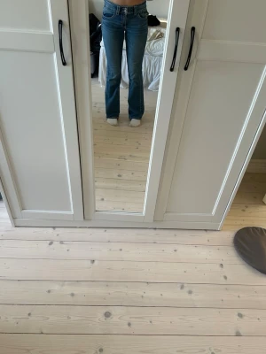 Blå bootcut jeans med låg midja - Säljer ett par blå bootcut jeans med låg midja. Jeansen har en snygg tvätt och utsvängda ben. Använd få gånger