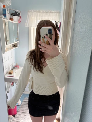 Krämvit omlottkofta med knytband - Säljer en krämvit stickad omlottkofta med breda ribbade muddar och knytband i midjan. Koftan har lång ärm och en croppad passform som ger en trendig look. Perfekt att styla över linne eller topp för en snygg lager-på-lager outfit. Tröjan är i storlek 158/164 men passar någon som har xxs/xs. Säljer för jag tycker det är lite kort i ärmarna på mig. Skicka gärna pris förslag🌸
