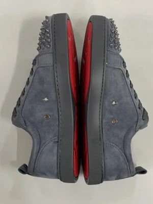 Gråa Louboutin sneakers med nitar - Snygga gråa sneakers från Christian Louboutin i mocka med ikoniska röda sulor. Använda 5-6 gånger. Skorna har coola silverfärgade nitar framtill och klassisk snörning. Perfekta för dig som vill sticka ut med en lyxig och edgy stil.