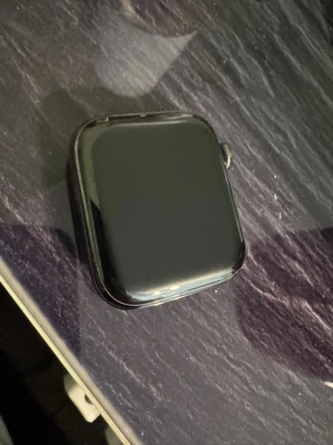 Svart Apple Watch Series 6 44mm  GPS + LTE (Steinless Steel) - Snygg svart Apple Watch Series 6 med fyrkantig pekskärm och aluminiumboett. Klockan har en digital krona med röd ring och en sidoknapp. Perfekt för att hålla koll på notiser, träning och hälsa direkt på handleden. Klarar alla uppgifter som en series 6 ska de.inga konstigheter. Jag säljer den för att jag har uppgraderat!