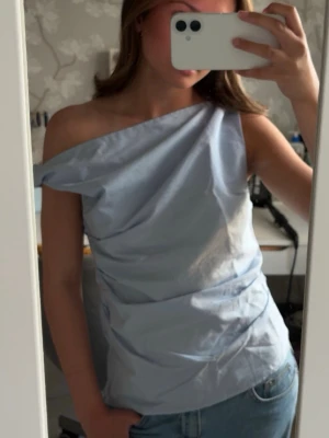 One shoulder-topp - Säljer en ljusblå one shoulder-topp från Pull & Bear, strl. XS🩵 Jättefin men får aldrig någon användning för den🥹 Använd 1 gång. Perfekt för lite finare tillfällen. Osäker om den fortfarande finns kvar på hemsidan.