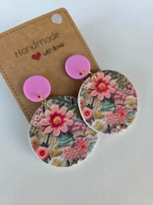 Handgjorda örhängen med blommönster - Unika handgjorda örhängen med stora runda hängen i färgglatt blommönster och rosa knappar upptill. Mönstret har en lätt 3D-effekt. Gjorda för hand av mig i polymerlera. 
