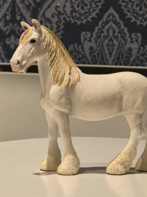 Schleich häst  - Säljer en vit schleich häst med ljusgul man och svans. Manen har små rosa detaljer och figuren har tydliga detaljer på ben och ansikte. 
