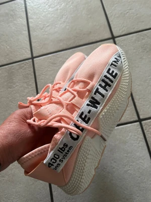 Ljusa rosa sneakers med textdetalj storlek 37 - Säljer ett par ljusrosa sneakers med vit sula och svart textdetalj på sidan. Skorna har mesh-överdel för bra ventilation och snörning framtill. Snygg och modern design med tydlig streetstyle-känsla.