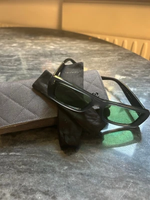 Chanel Solglasögon - Säljer ett par fantastiskt snygga och eleganta solglasögon från Chanel. Modellen är en klassisk, rektangulär acetatbåge som passar till allt och ger en exklusiv touch till vilken outfit som helst. Inga repor eller defekter!!      Bågen kommer i en sofistikerad mörkgrå/grön ton (färgkod S8002) med matchande gröna glas. Ljusingen är behaglig (kategori 2), vilket gör dem perfekta för både stark vårsol och varma sommardagar utan att kännas för mörka. nypris €700
