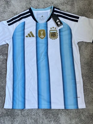 Argentina 2026 adidas Fotbollströja – Strl M - Argentina 2026 fotbollströja från adidas i mycket fint skick. Klassisk design med hög komfort och bra passform. Passar perfekt för både användning och samling.                                                                                                        Storlek: Medium Skick: Ny med lapp