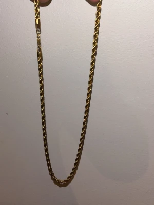 Cordell  halsband - Snyggt guldfärgat halsband med tvinnad kedja som ger en exklusiv känsla. Halsbandet har en klassisk design och passar perfekt för dig som gillar stilrena accessoarer. Låset är diskret och smidigt. Perfekt att bära till olika outfits för en trendig look. 60 cm 