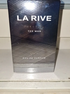 La Rive Prestige The Man Grey EdP - La Rive Prestige The Man Grey Eau de Parfum är en stilren herrparfym i en snygg grå och silverfärgad förpackning. Doften är inspirerad av fransk elegans och passar dig som vill ha en modern och maskulin parfym. Flaskan är tillverkad av glas och kartongen har metallicfinish.