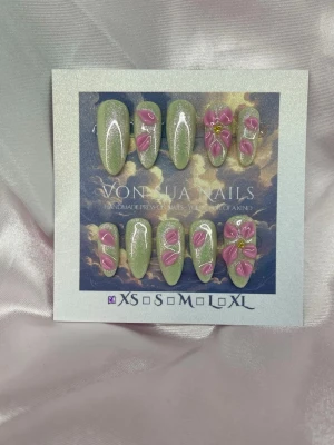 Kamelia (XS);Meidum Almomd - Snygga handgjorda press-on naglar i glittrigt ljusgrönt med handgjord 3D rosa blommor och gulddetaljer. Naglarna har en medium lång mandelformad design och kommer i XS: 14 mm, 11 mm, 11,5 mm, 10 mm, 8 mm. Perfekt för dig som vill ha en unik och kreativ look.